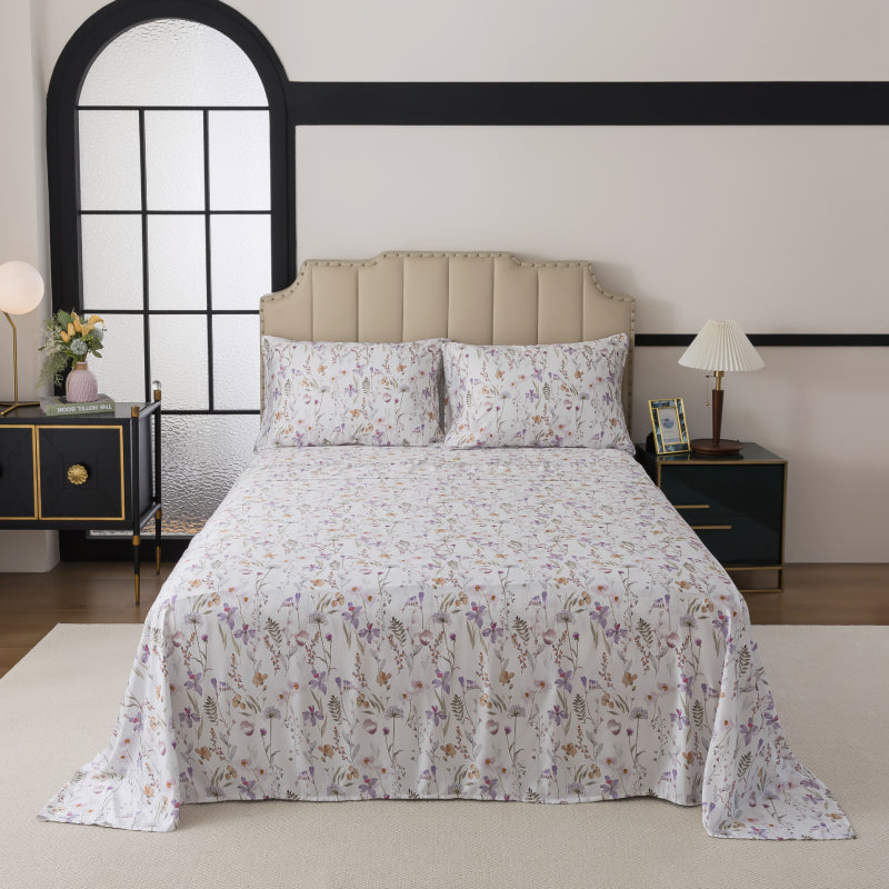 Floral-patterned bedspread on a bed in a bedroom setting with nightstands and decor.