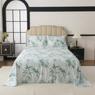 Bed with green leaf patterned bedding in a bedroom setting.