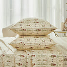 Bed with red rose patterned bedding and pillows on a neutral background