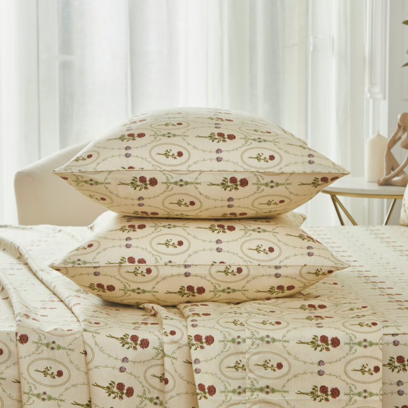 Bed with red rose patterned bedding and pillows on a neutral background