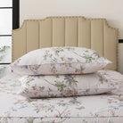 Bed with red floral patterned bedding and pillows on a neutral background